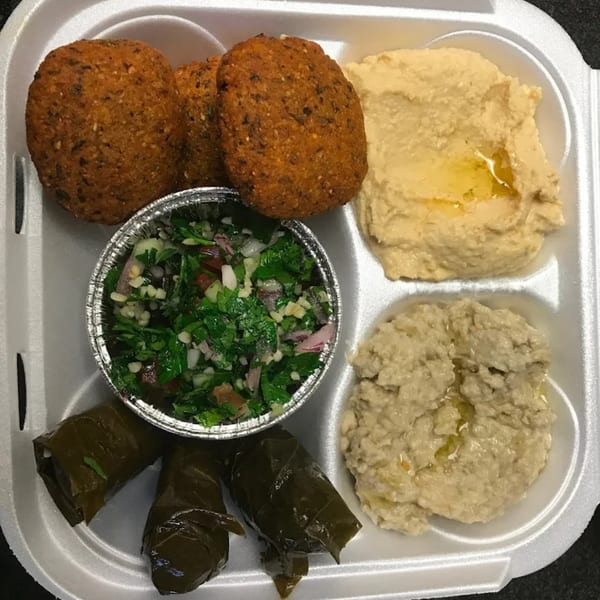 A Mediterranean platter with falafel, hummus, baba ghanoush, tabbouleh, and stuffed grape leaves.